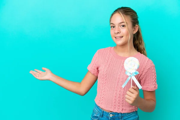Little Caucasian Girl Holding Lollipop Isolated Blue Background Extending Hands — Stock Photo, Image