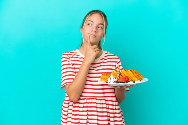 Little Caucasian Girl Holding Waffles Isolated Blue Background Having Doubts — Stock Photo, Image