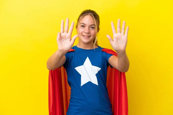 Super Hero little girl isolated on yellow background counting nine with fingers