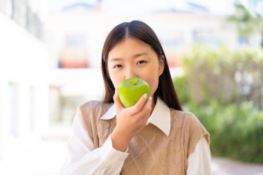 Dışarıdaki güzel Çinli kadın elinde elma tutuyor.