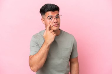 Pembe arka planda izole edilmiş beyaz yakışıklı bir adam bir şey gösteriyor.