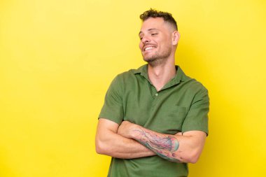 Sarı arka planda izole edilmiş genç beyaz yakışıklı adam mutlu ve gülümsüyor.