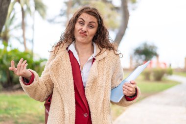 Omuzlarını kaldırırken şüpheyle hareket eden genç bayan öğrenci.