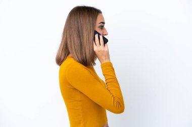 Beyaz arka planda izole edilmiş genç beyaz bir kadın cep telefonuyla sohbet ediyor.