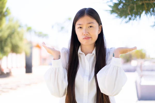 Hübsche Chinesin Freien Mit Zweifeln Beim Händeheben — Stockfoto