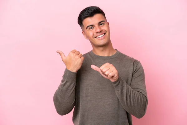 stock image Young caucasian handsome man isolated on pink background pointing to the side to present a product