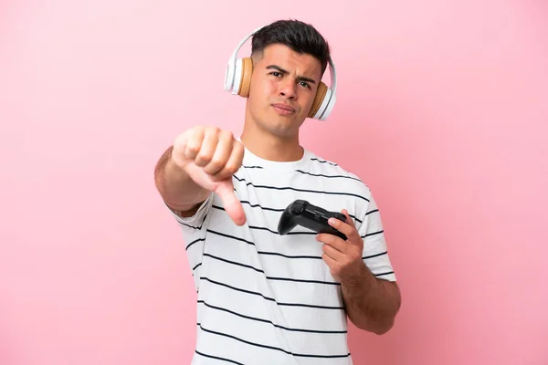 Νέος Όμορφος Άνδρας Παίζει Ένα Χειριστήριο Βιντεοπαιχνιδιών Απομονωμένο Ροζ Φόντο — Φωτογραφία Αρχείου