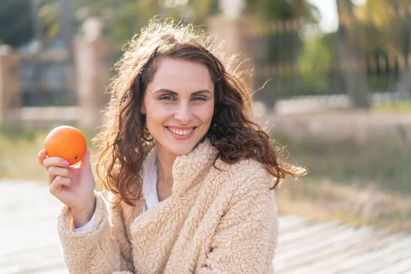 若いですCaucasian女性で屋外で保持Aオレンジ — ストック写真