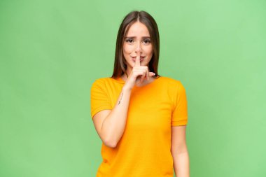 İzole edilmiş arka planda genç, beyaz bir kadın sessizce hareket ettiğini gösteriyor. Parmağını ağzına sokuyor.