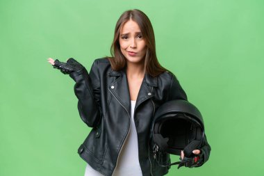 İzole edilmiş arka planda motosiklet kaskı olan, genç, beyaz bir kadın el kaldırırken şüphe duyuyor.