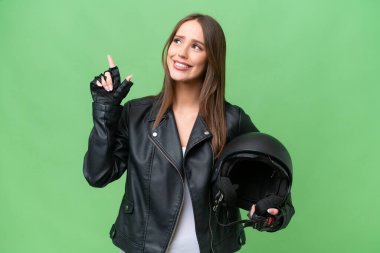 Motosiklet kaskı takmış genç, beyaz bir kadın izole edilmiş arka planda harika bir fikre işaret ediyor.