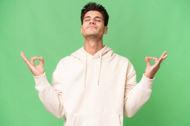 Zen pozunda soyutlanmış beyaz, yakışıklı genç bir adam.