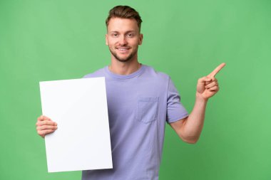 Sarışın, beyaz, soyutlanmış bir arka planı olan, elinde boş bir levha olan genç bir adam.