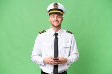 Uçak pilotu izole edilmiş arka planda cep telefonuyla mesaj gönderiyor.