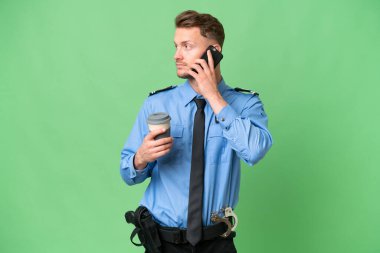 Arka planda izole edilmiş genç bir polis kahve ve bir cep telefonu tutuyor.