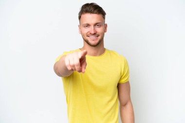 Beyaz arka planda izole edilmiş genç sarışın adam mutlu bir ifadeyle öne bakıyor.