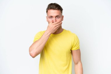 Beyaz arka planda izole edilmiş beyaz tenli genç sarışın adam ağızlarını eliyle kapatıyor.