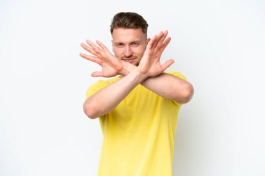 Beyaz arka planda izole edilmiş genç, sarışın, beyaz bir adam gergin ellerini öne uzatıyor.