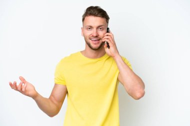 Beyaz arka planda izole genç sarışın beyaz adam cep telefonuyla sohbet ediyor.