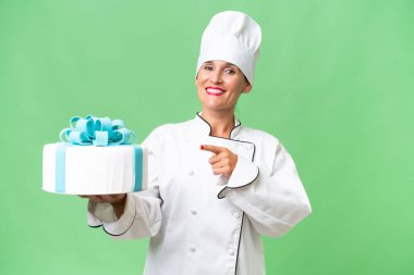 Orta yaşlı beyaz bir kadın, izole edilmiş arka planda büyük bir pastası var.