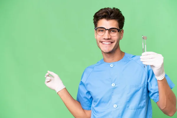 Young Dentist Man Holding Tools Isolated Background Pointing Finger Side — Stock Photo, Image