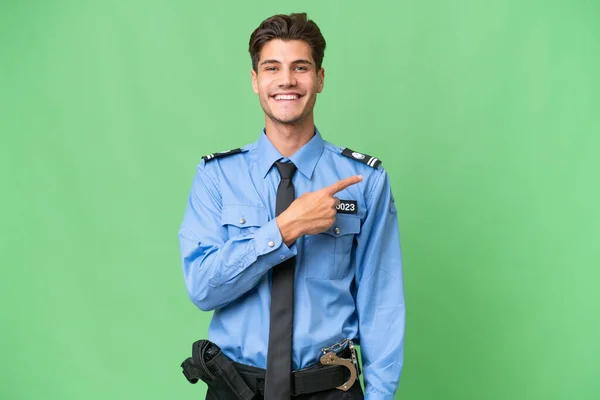Młody Policjant Odosobnionym Tle Wskazując Bok Aby Przedstawić Produkt — Zdjęcie stockowe
