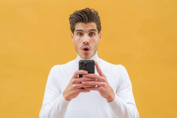 Young Caucasian Man Outdoors Looking Camera While Using Mobile Surprised — Stock Photo, Image