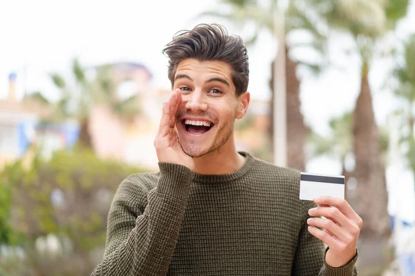 Young Caucasian Man Holding Credit Card Outdoors Shouting Mouth Wide — Stock Photo, Image