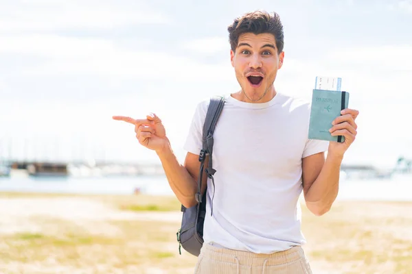 Jonge Blanke Man Met Een Paspoort Buitenlucht Verrast Wijzend Vinger — Stockfoto