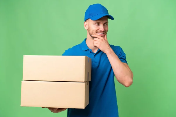 Stock image Delivery caucasian man over isolated background looking to the side and smiling