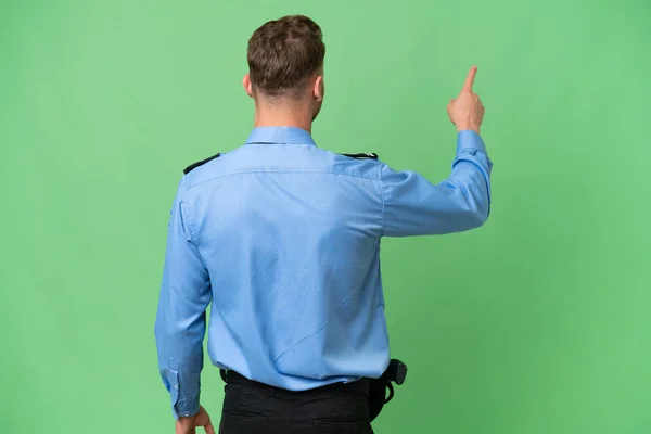 Jonge Politieman Geïsoleerde Achtergrond Wijzend Terug Met Wijsvinger — Stockfoto