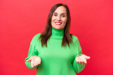 Orta yaşlı beyaz kadın kırmızı arka planda izole edilmiş mutlu ve gülümsüyor.