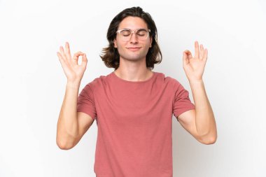 Zen pozisyonunda beyaz arka planda izole edilmiş yakışıklı bir genç.