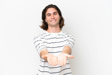 Beyaz arka planda izole edilmiş genç yakışıklı bir adam bir ilan vermek için avucunun içinde hayali bir alan tutuyor.