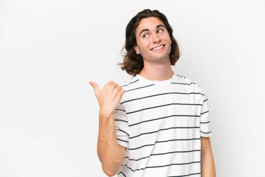 Beyaz arka planda izole edilmiş genç yakışıklı bir adam bir ürün sunmak için kenarı işaret ediyor.