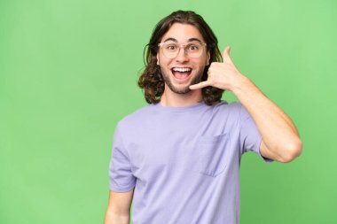 Soyutlanmış bir geçmişi olan yakışıklı genç bir adam telefon jesti yapıyor. Bana geri dönüş işareti ver.