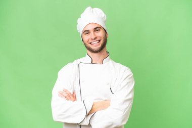 Genç, yakışıklı aşçı, izole edilmiş arka planda kollarını ön cephede çapraz tutuyor.