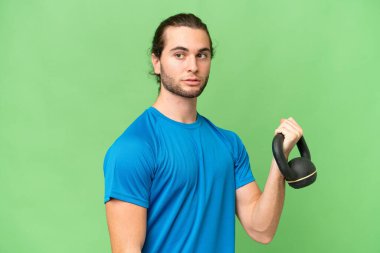 Yeşil krom arka planda izole edilmiş genç yakışıklı adam halter olarak ağırlık kaldırıyor.
