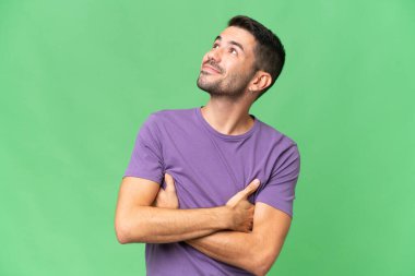 Genç, yakışıklı, beyaz, soyutlanmış bir adam gülümserken yukarı bakıyor.