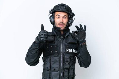Beyaz arka planda izole edilmiş genç beyaz SWAT elemanı Tamam işareti ve baş parmak hareketi gösteriyor