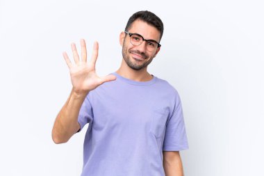 Beyaz arka planda izole edilmiş genç beyaz adam parmaklarıyla beşi sayıyor.