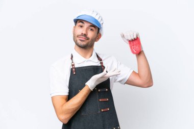 Kasap beyaz önlük giymiş ve soyutlanmış beyaz arka planda taze et servis ediyor. Davet edildiği için ellerini yana uzatıyor.