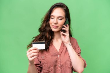 Young caucasian woman over isolated background buying with the mobile with a credit card