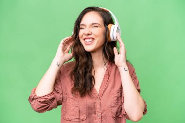 Young caucasian woman over isolated background listening music and singing