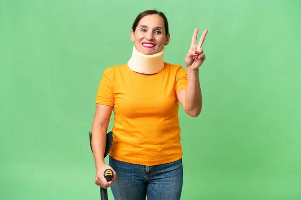 Stock image Middle-aged caucasian woman wearing neck brace over isolated background smiling and showing victory sign