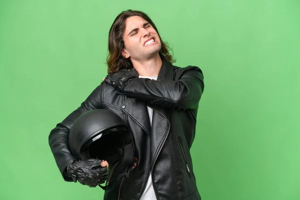 年轻英俊男子 头戴摩托车头盔 背景为绿色 肩头因努力而疼痛 — 图库照片