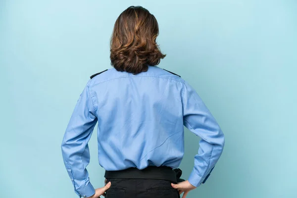 stock image Young police caucasian man isolated on blue background in back position