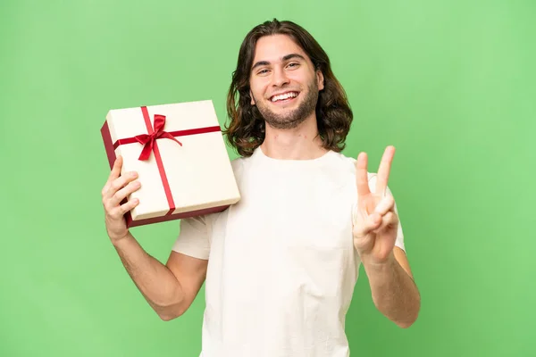 Jonge Knappe Man Met Een Geschenk Geïsoleerde Achtergrond Glimlachen Tonen — Stockfoto
