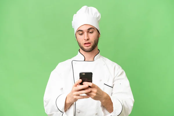 stock image Young handsome chef man over isolated background sending a message with the mobile