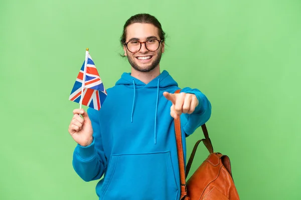年轻英俊男子举着英国国旗 身披孤立的背景 惊讶地指着前方 — 图库照片